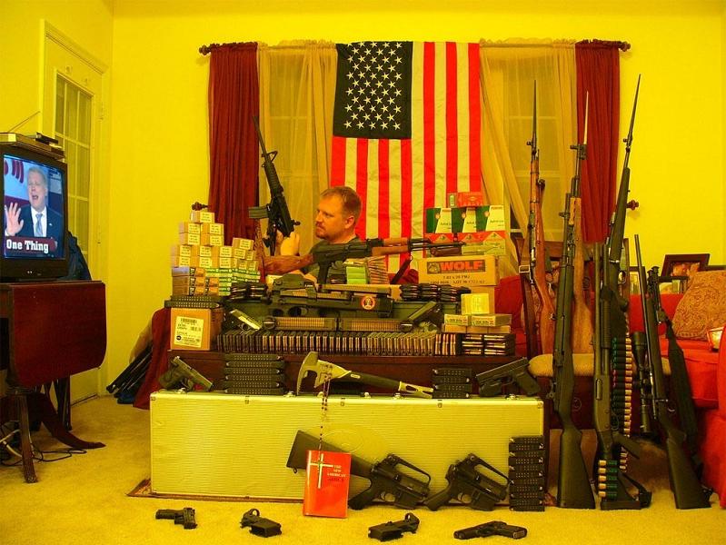man in living room with lots of guns and american flag Picture of the Day   March 11, 2010