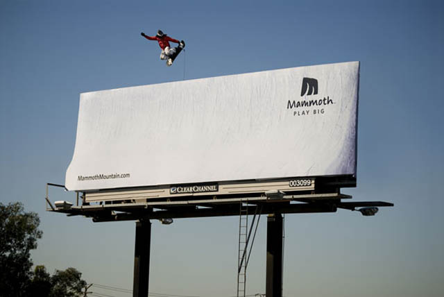 snowborder doing big air grab off billboard