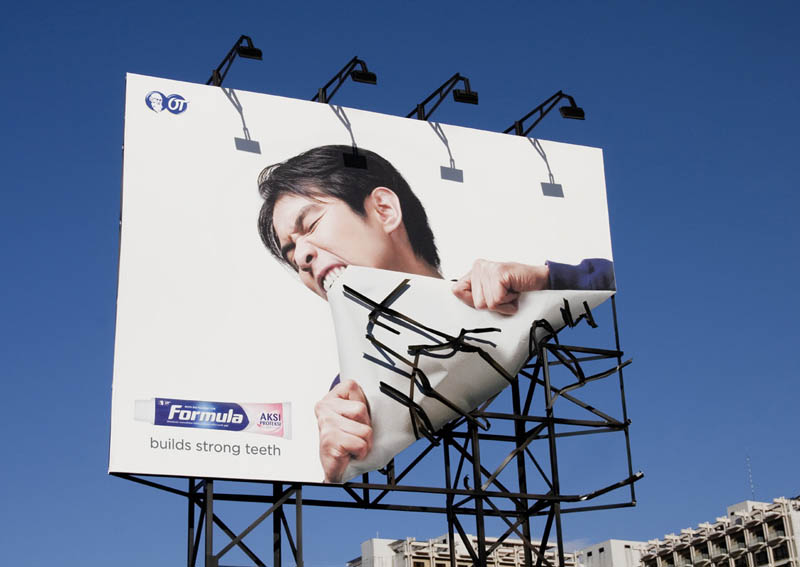 billboard of person ripping up actual billboard with teeth to promote toothpaste