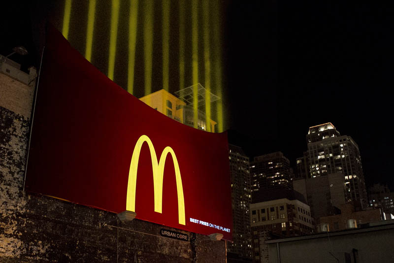 mcdonalds billboard shows fries box with lights shining upwards like french fries