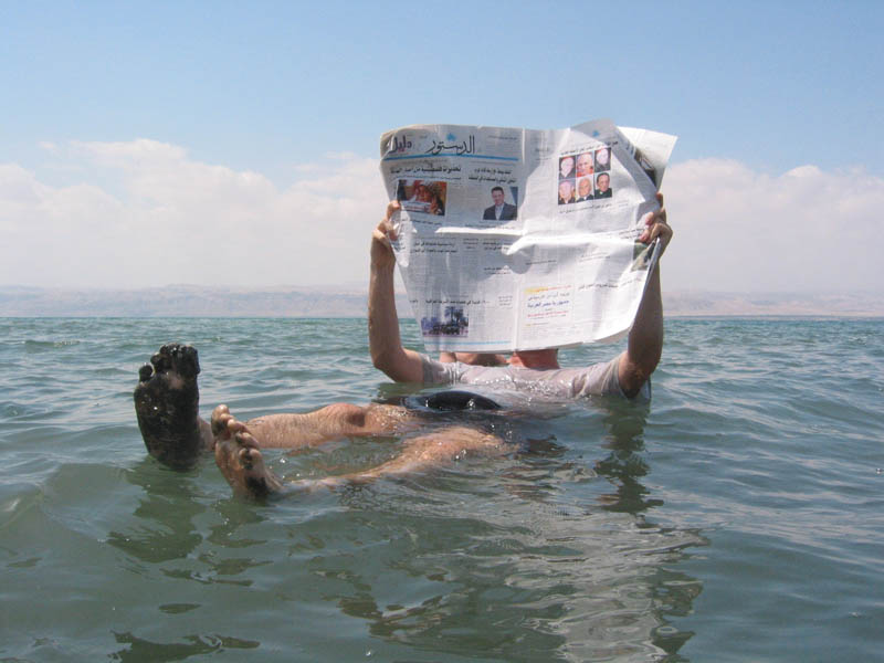 person floating in the dead sea reading a newspaper