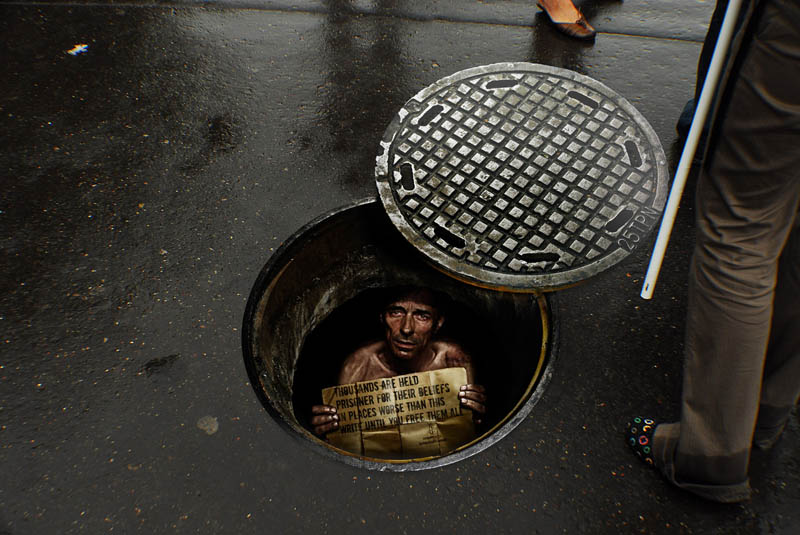 sidewalk sticker looks like a person is inside a manhole looking up at you in despair