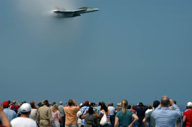 crowd of people watching a plane break the sound barrier