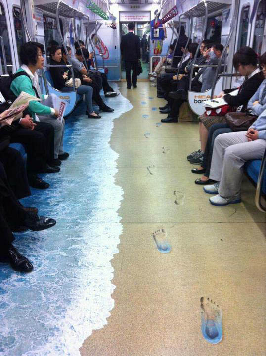 floor sticker decal on subway makes it look like a sandy beach with footprints and waves