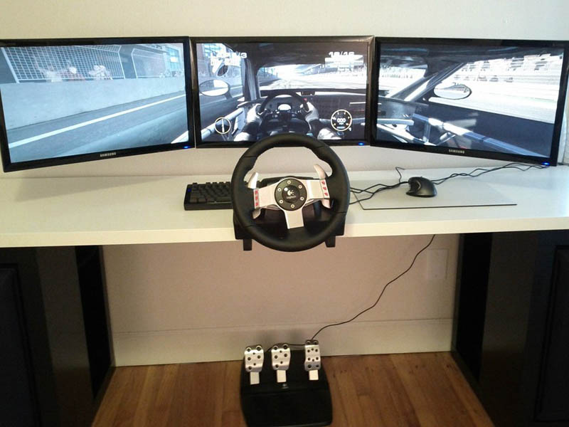 three monitor set up for racing game with steering wheel and pedals 