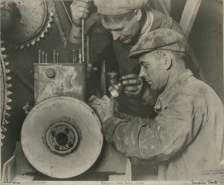 Two workers repairing machinery (1931)