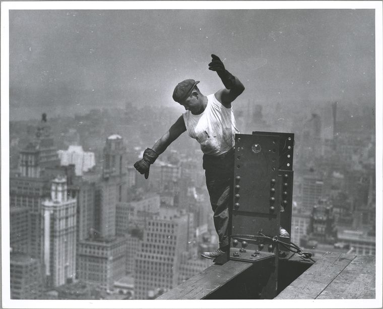 Worker on Empire State building, signaling the hookman high up unsecured standing on beam