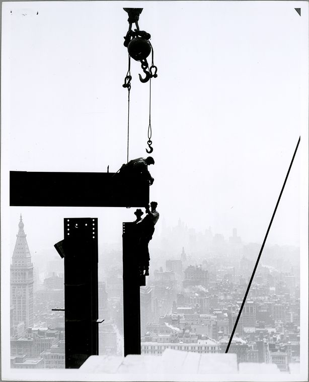 silhouette of Workers on Empire State building with city in background