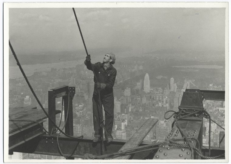 Construction worker standing on an I-beam pulling a rope (1931)