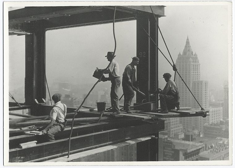 Riveters attaching a beam sitting on small wooden platform unsecured 1931