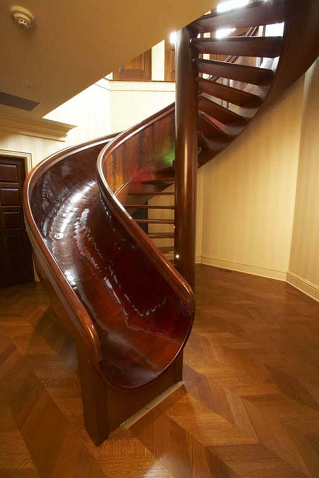 indoor spiral staircase made of wood with a slide integrated into it