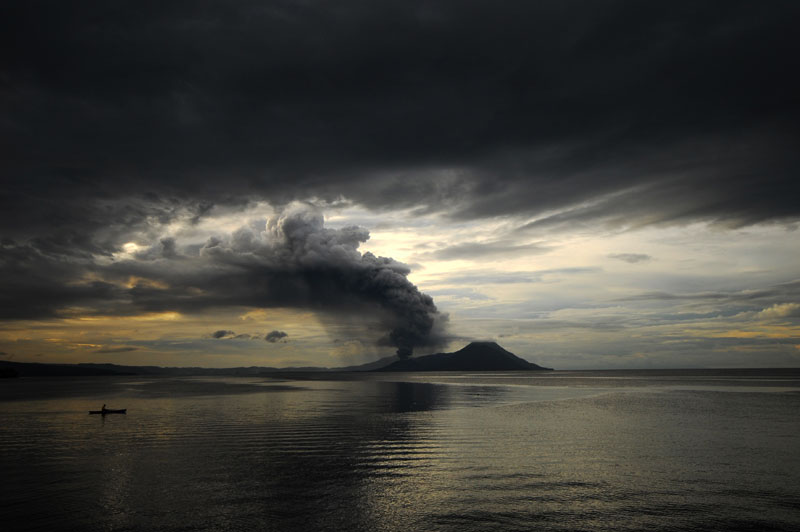 lone fisherman with volcano behind ash plume Picture of the Day: The Lone Fisherman