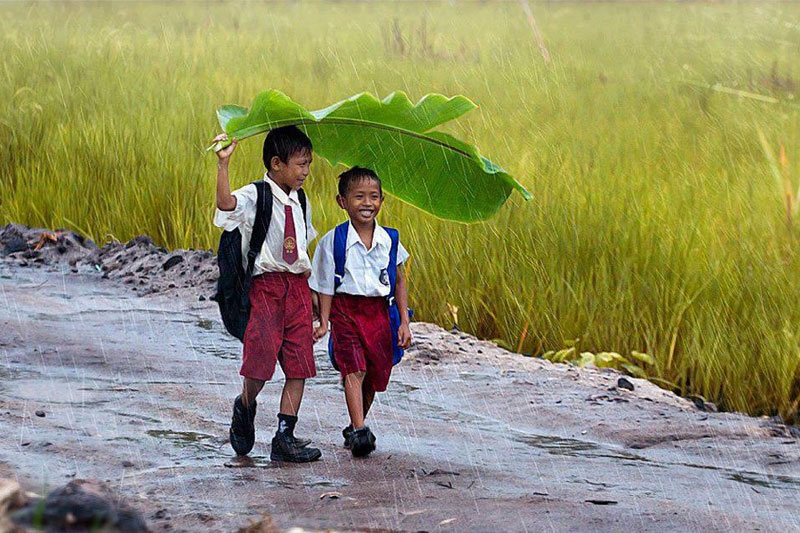two kids under a banana leaf in the rain indonesia The Top 50 Pictures of the Day for 2013