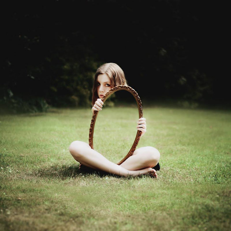 woman holding mirror on grass reflection Picture of the Day: Invisible Reflection