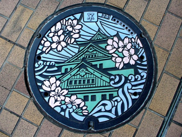 Close-up of intricate Japanese manhole cover art showing vibrant colors and patterns