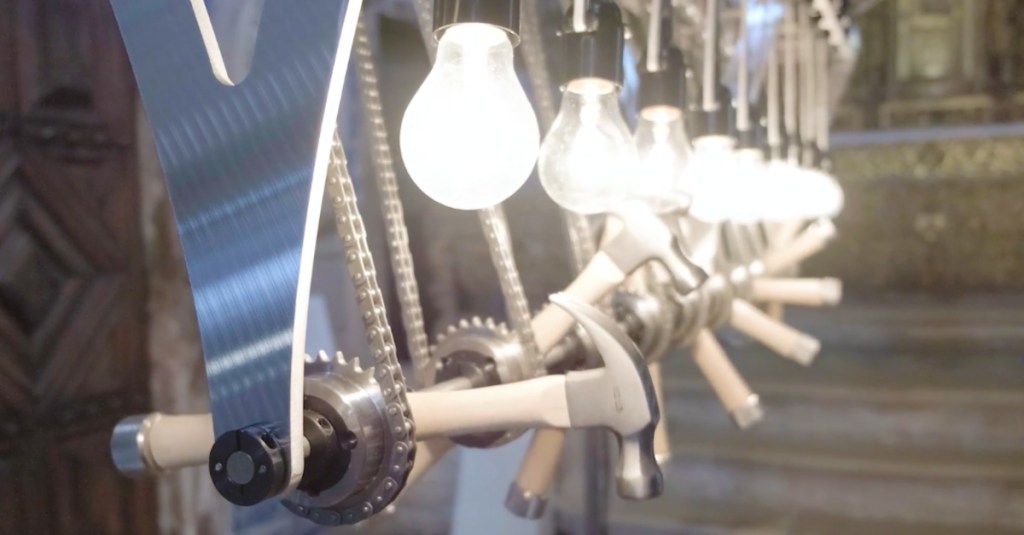 A Kinetic Sculpture With Light Bulbs and Hammers in Motion