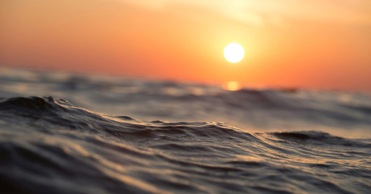 Shot of the ocean with the sunset in the background