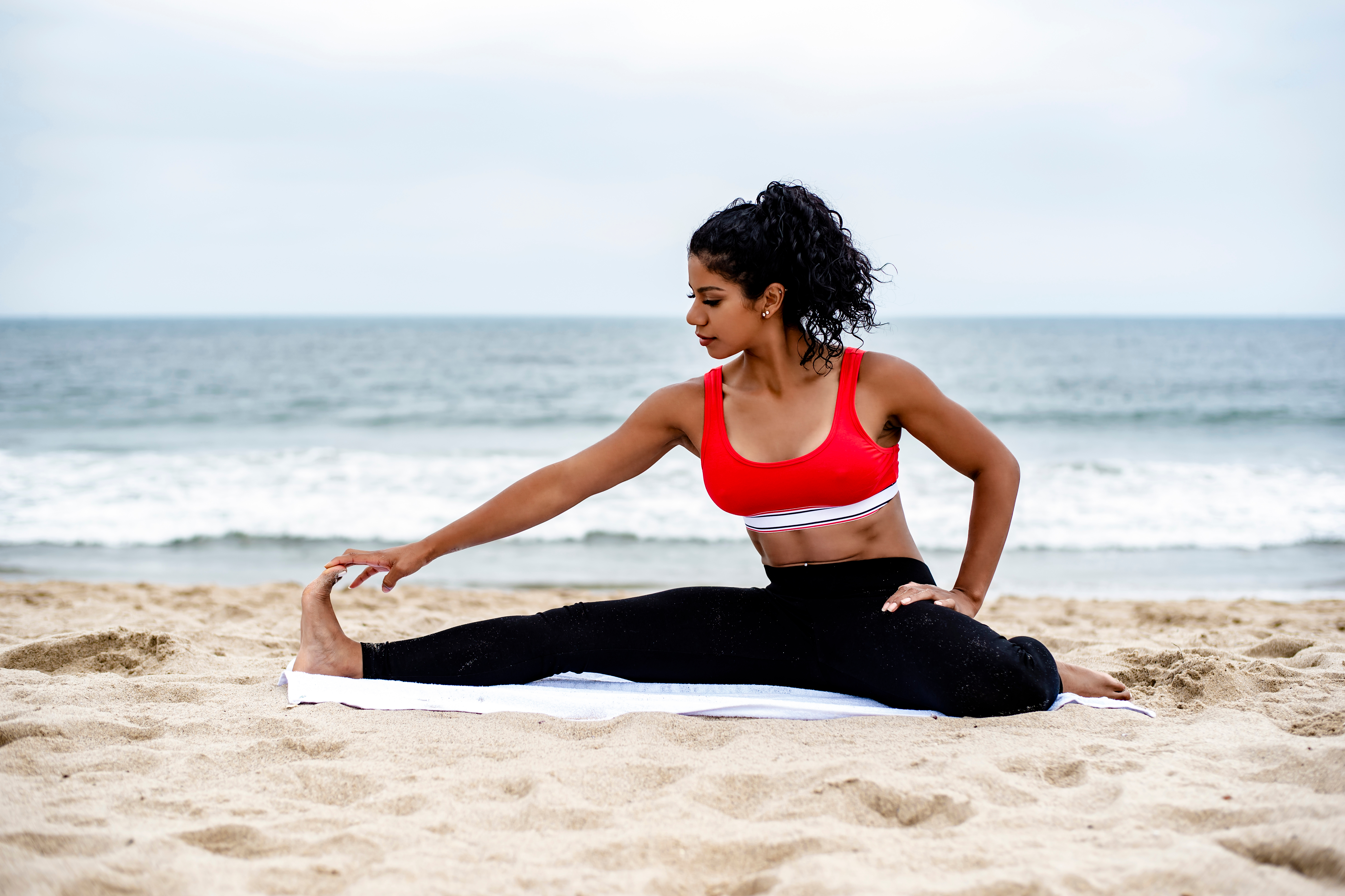 woman on a beach stretching on a towel