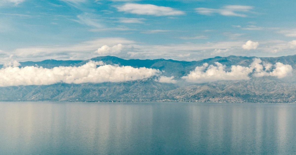 A lake with mountains and a cloudy sky