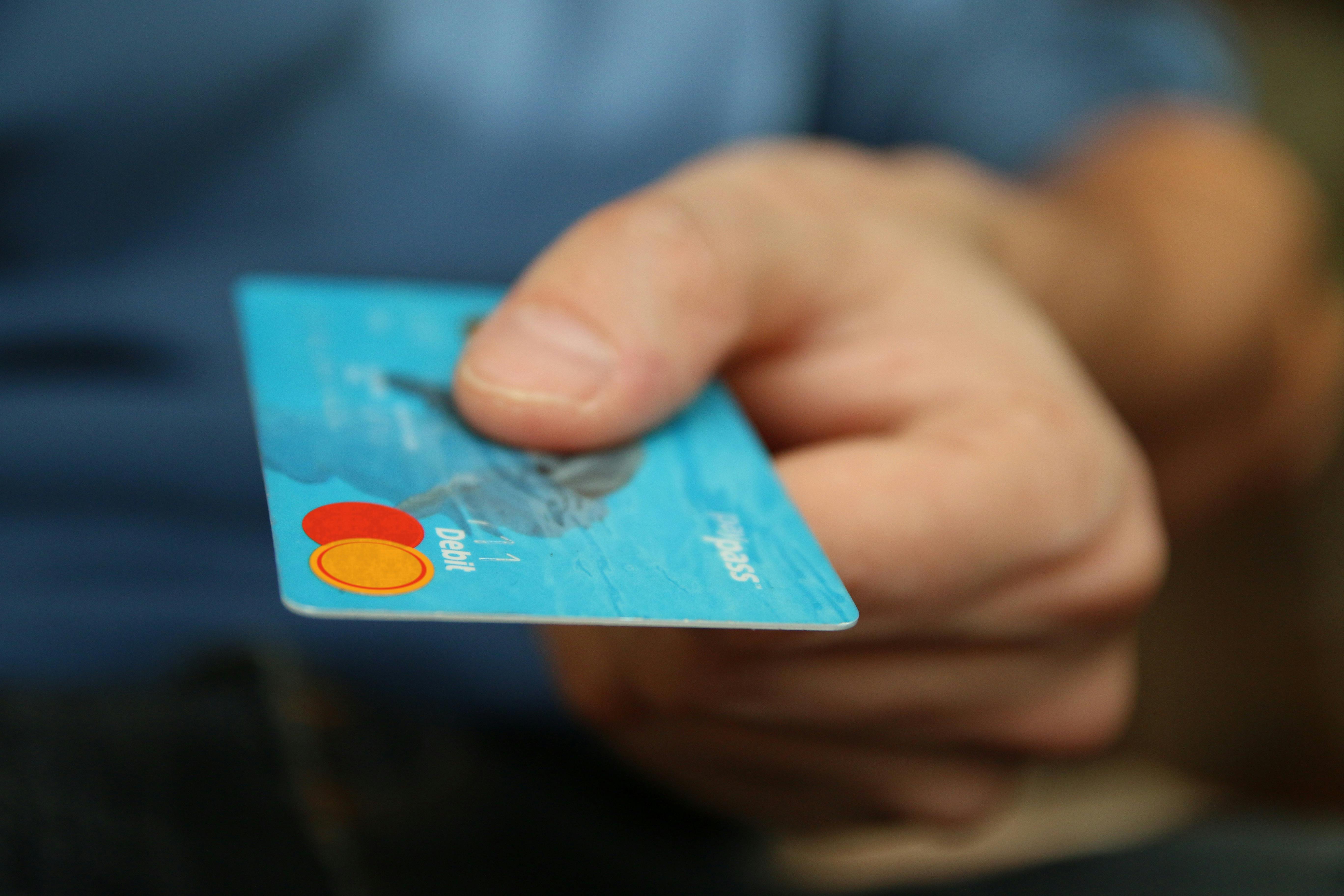 Hand holding a turquoise debit card