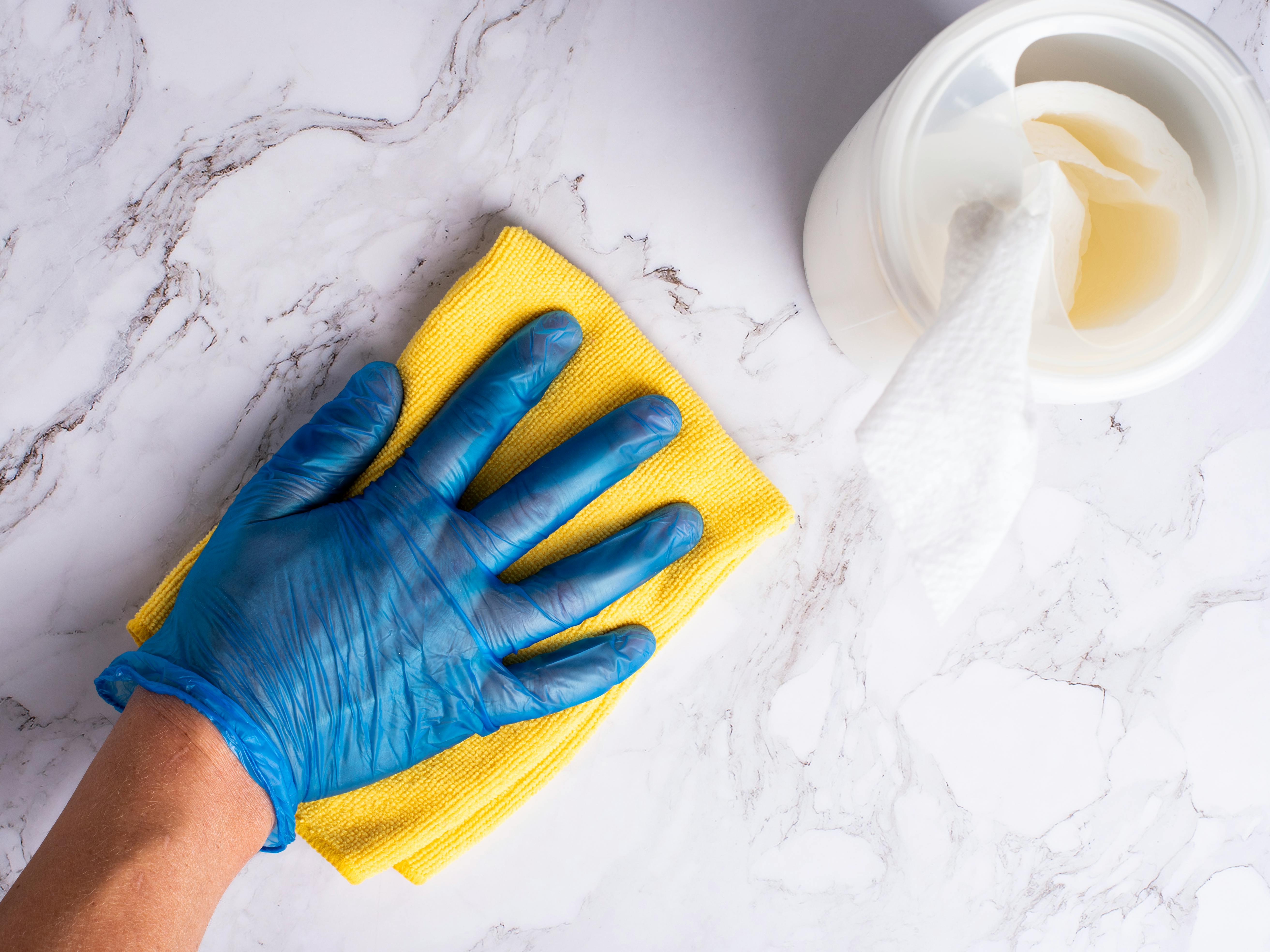 rubber gloved hand wiping down a granite countertop