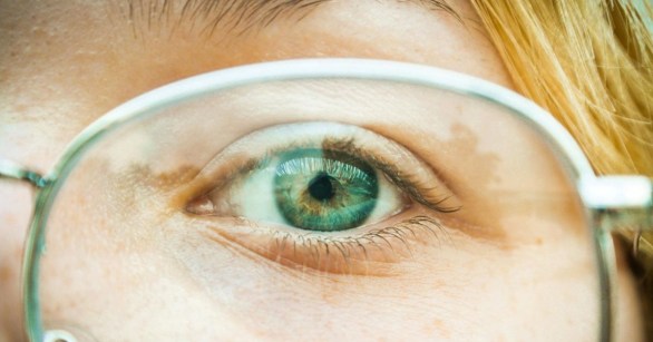 Green eye behind wire glasses