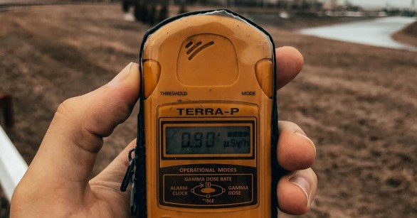 A yellow Geiger counter held in a hand