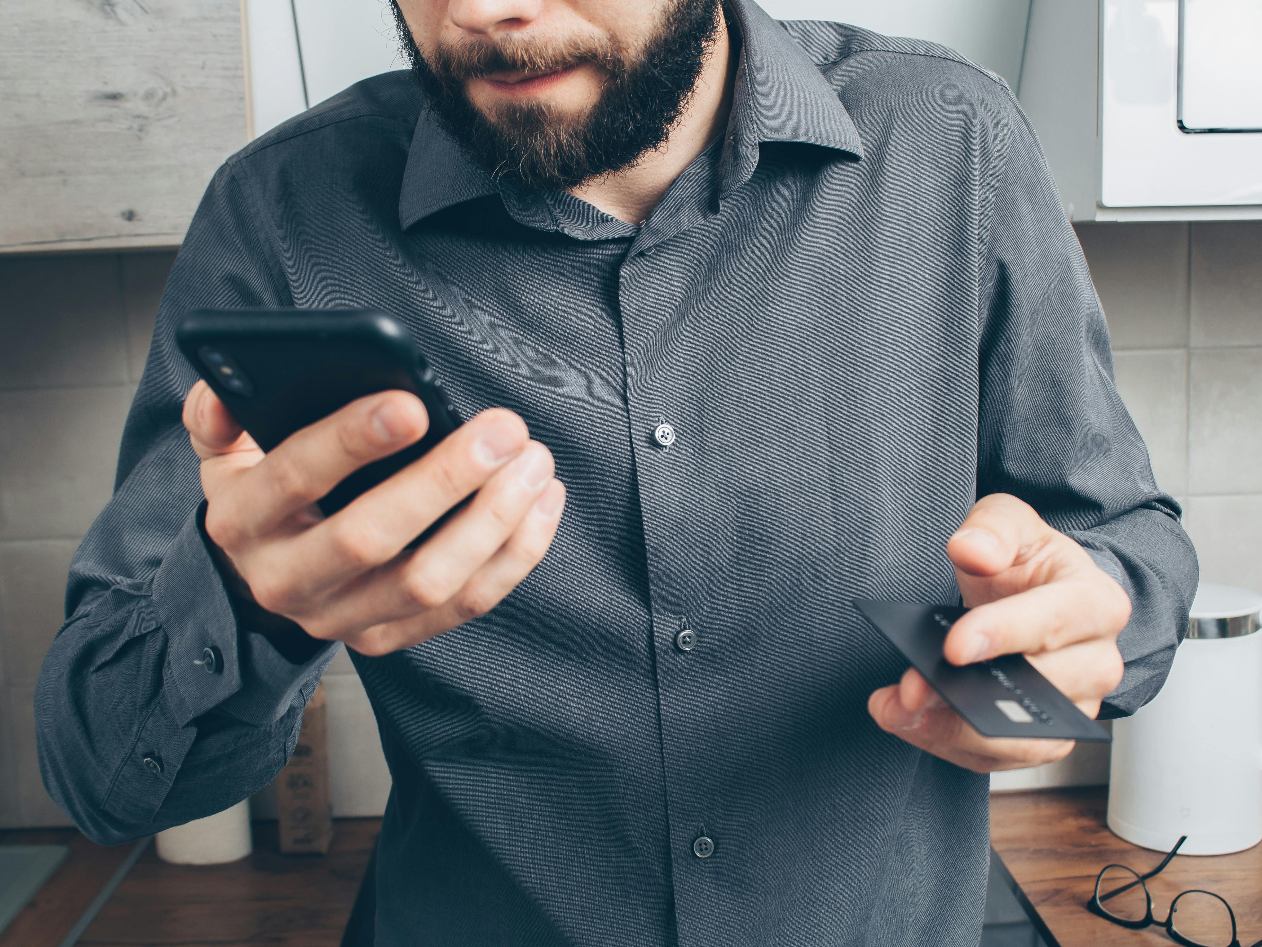 Bearded man holding phone and debit card