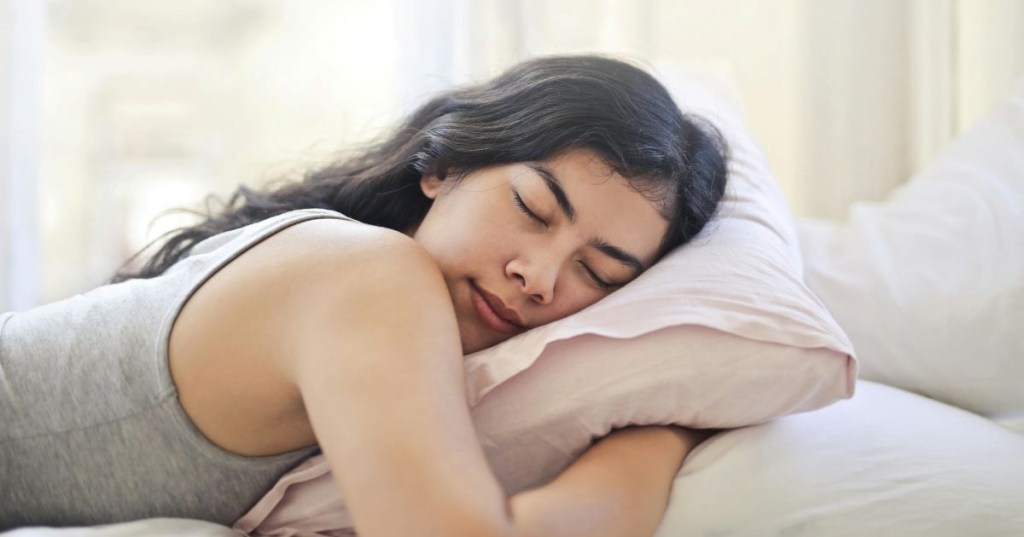 A woman hugging a pillow as she sleeps