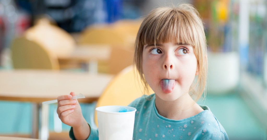 little girl sticking out blue tongue slushy