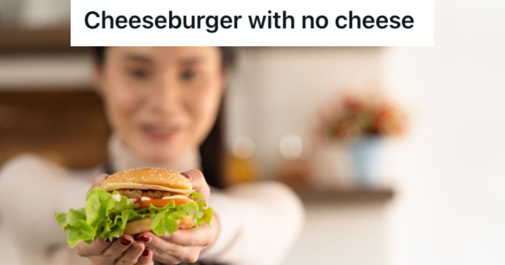 woman holding up and handing over a hamburger with a smile