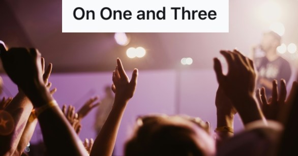 Audience clapping and raising their hands before a musician playing on stage