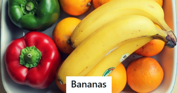 Bananas laying on top of a bowl of fruit