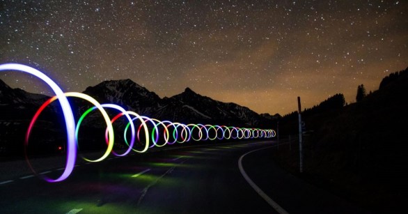 Swirling lights by a road against the night sky