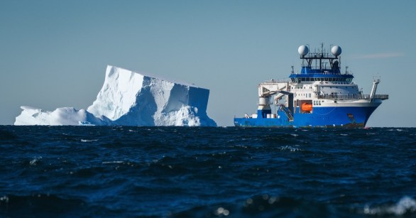 A research vessel beside a detached iceberg