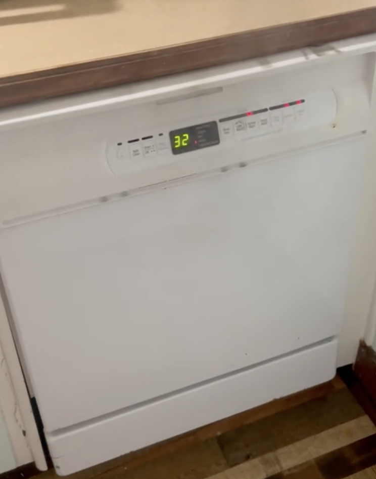 a white dishwasher with smoke coming out of it