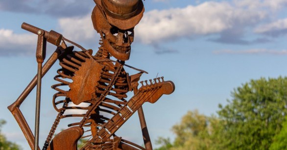 A metal statue of a skeleton playing guitar
