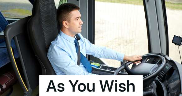 man in a blue shirt and tie driving a tour bus