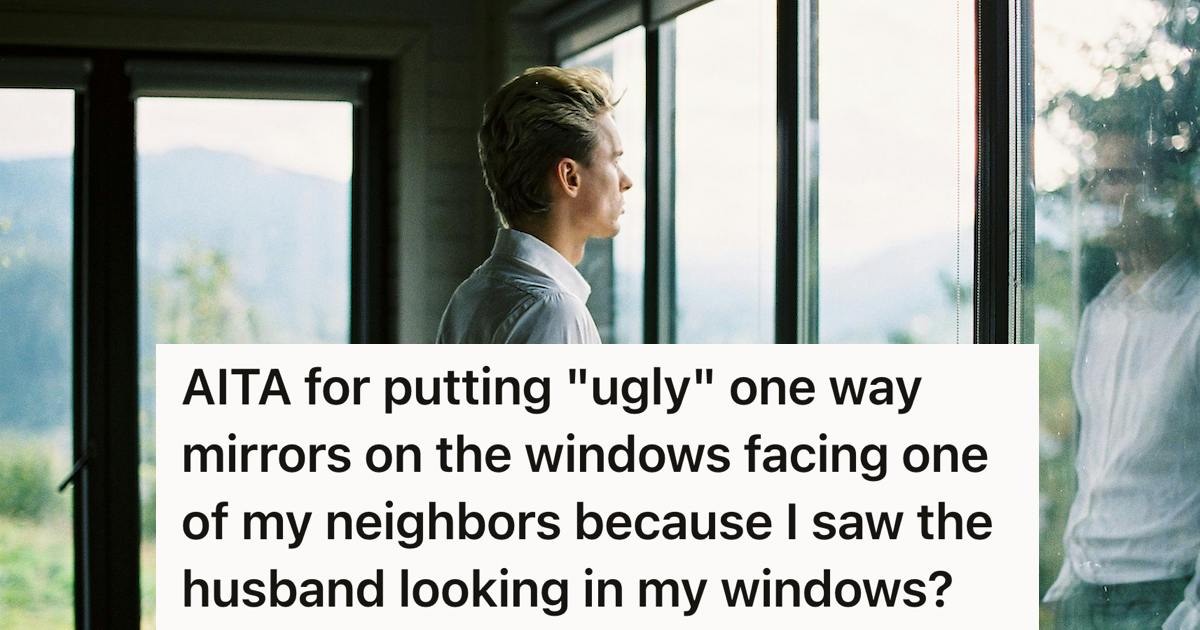 a man looks out some large windows with his reflection shining in one