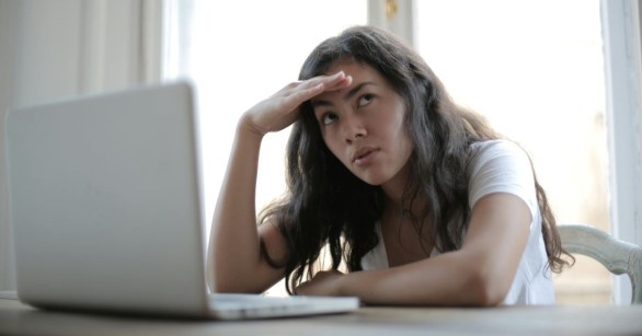 A woman using a laptop, looking confused