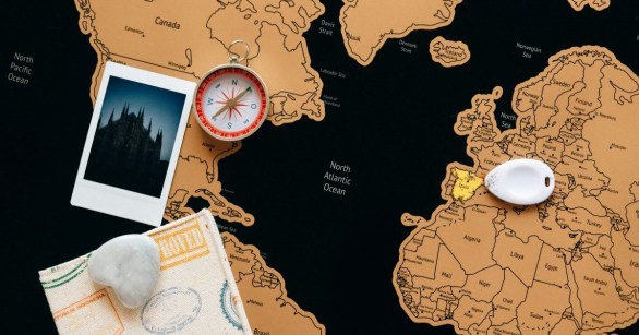A world travel map with a compass and polaroid photograph