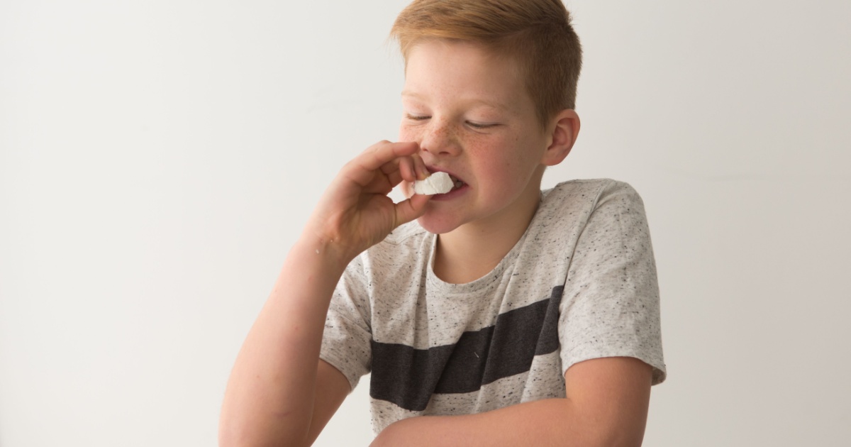 Young boy eating marshmallow