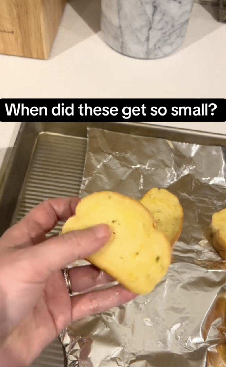 person holding a piece of garlic bread