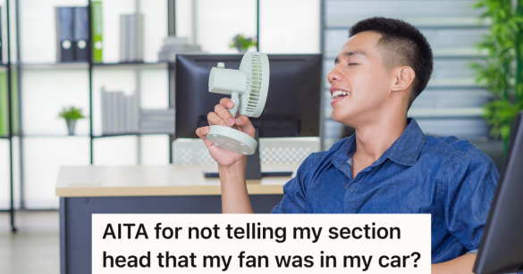 man at a desk holding a small fan up to his face
