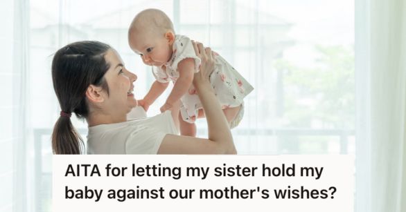 Little girl happily holding a baby up high in the air