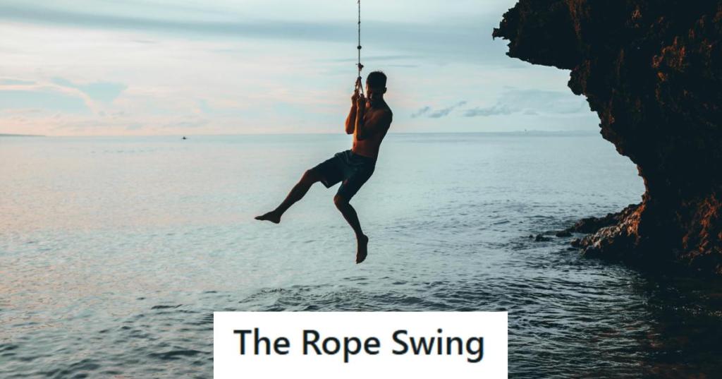 Man swinging off a rope swing into water below