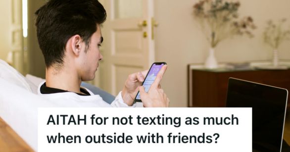 Man texting on. his phone while sitting on the couch with his laptop