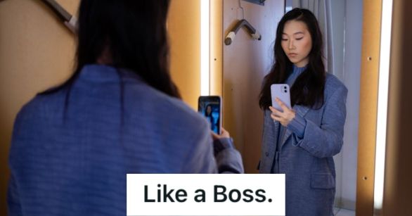 Woman fitting clothes in the fitting room and taking a mirror selfie