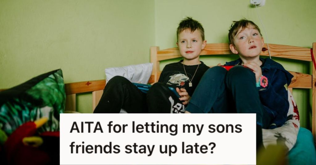 Two young boys playing video games while sitting on the bed