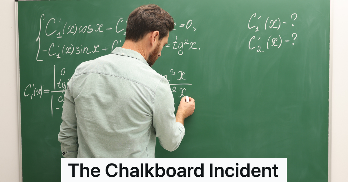 male teacher with a beard writing on a green chalkboard